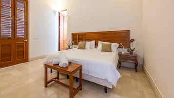 Un dormitorio ordenado con una cama grande, mesitas de noche y una pequeña mesa de madera con toallas.