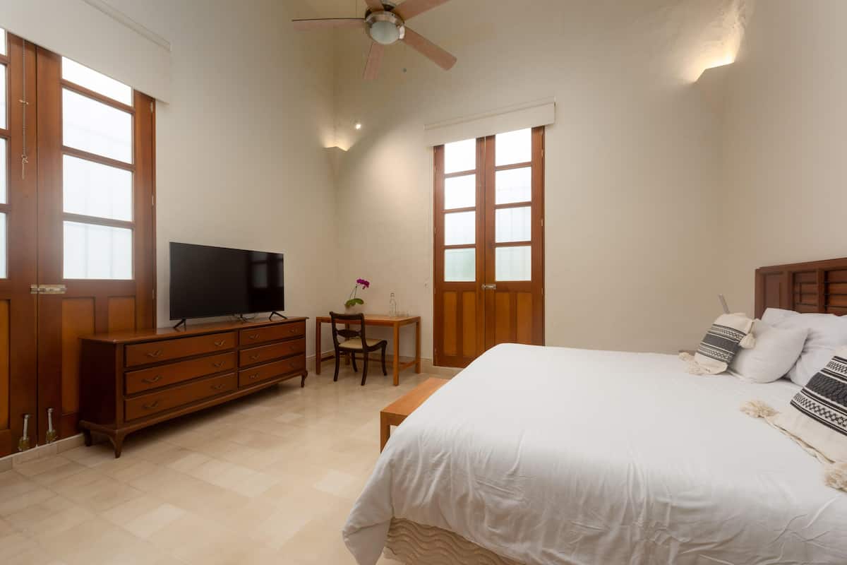 A bedroom with a bed, a TV, a desk, and a chair.