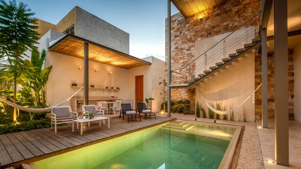 A modern outdoor pool area with a wooden deck, lounge chairs, and a staircase leading to an upper level. - Villa Orquidea Boutique Hotel (Mérida)