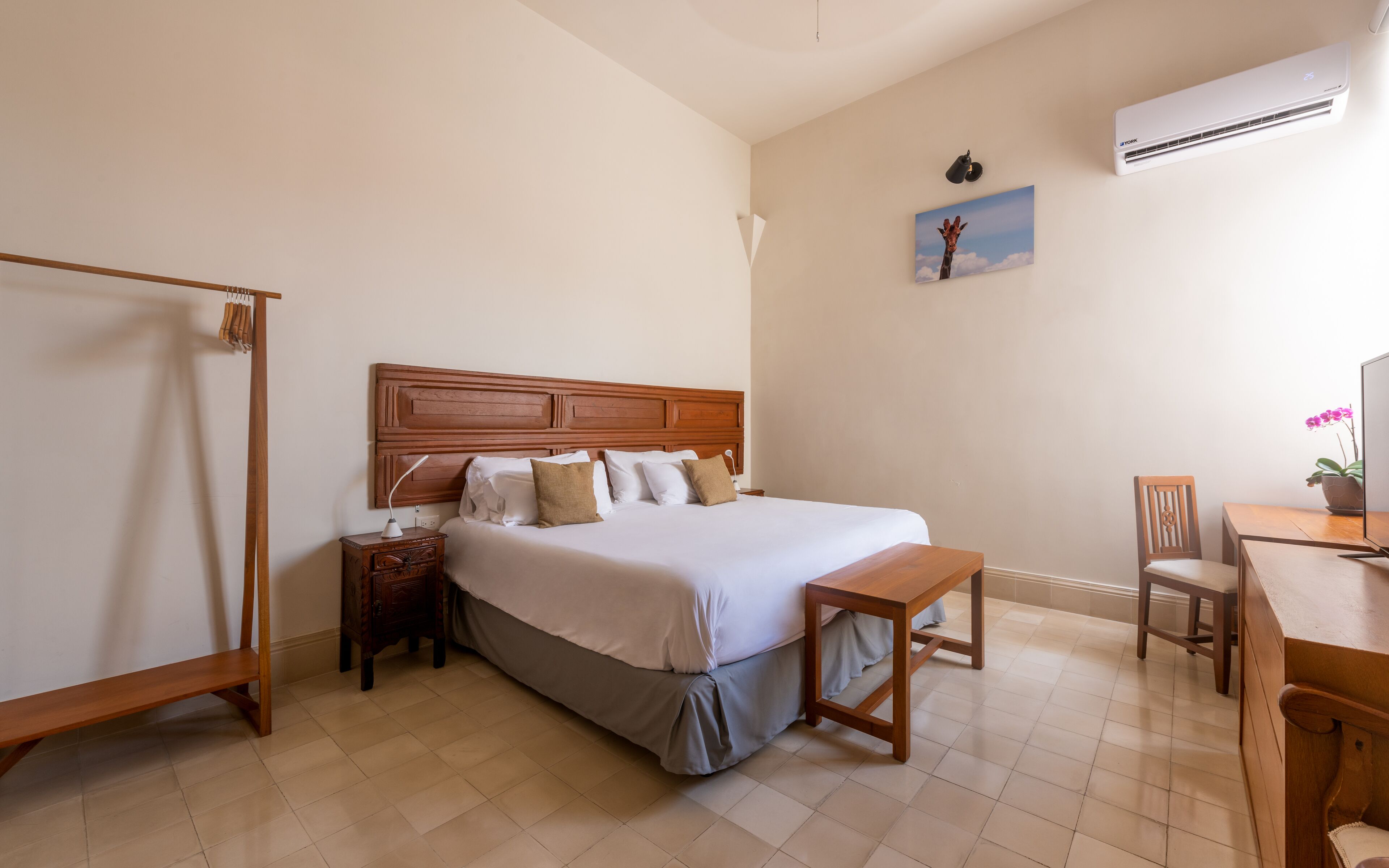 A bedroom with a wooden bed, a nightstand, a desk, and a chair.