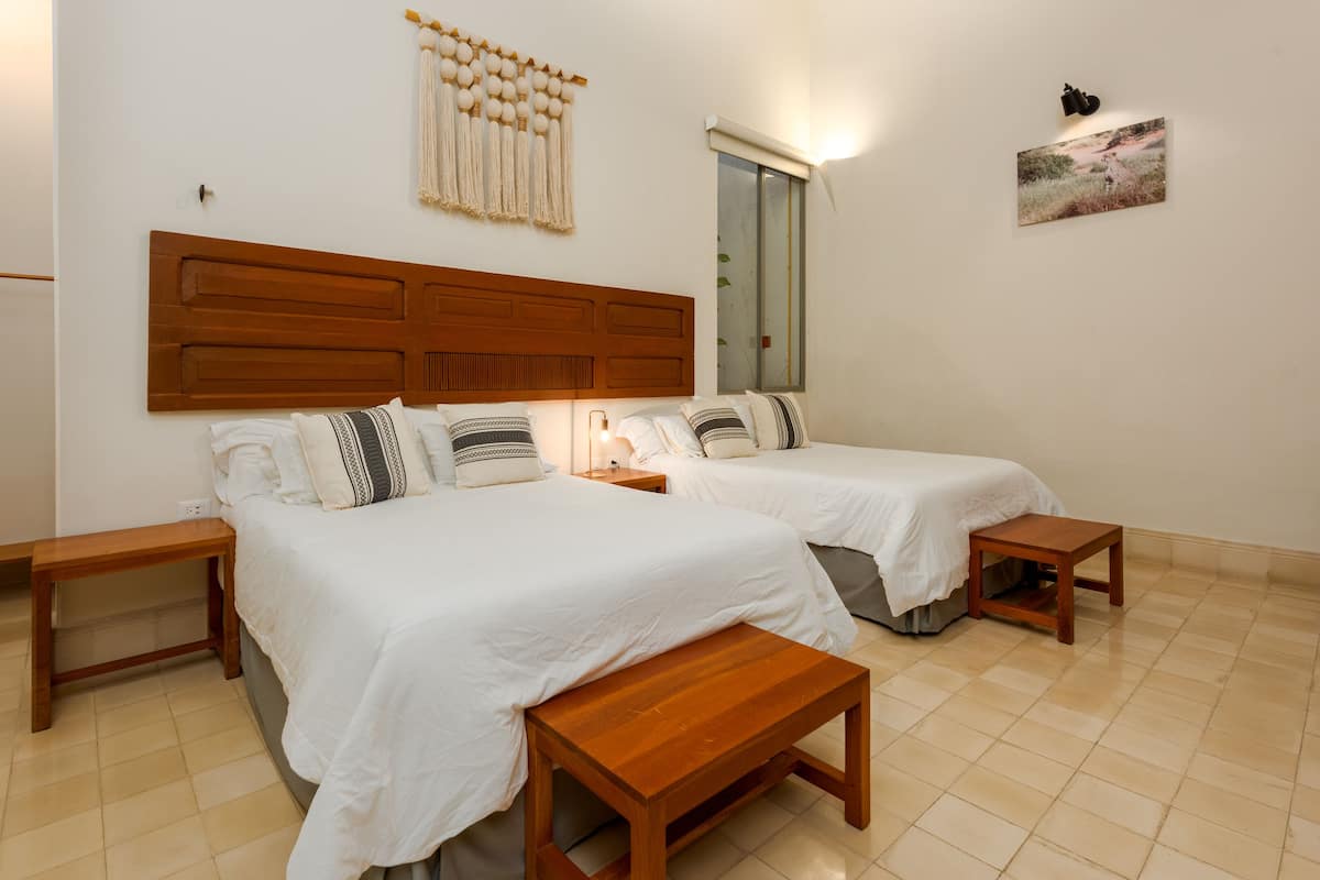 A double room with two beds, wooden headboards, bedside tables, and a bench.
