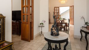 A spacious living area with a large wooden door, a chandelier, a dining table, and a patterned rug. - Villa Orquidea Boutique Hotel (Mérida)