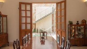 A dining area with a wooden table and chairs, a chandelier, and a view of a staircase leading to a balcony. - Villa Orquidea Boutique Hotel (Mérida)