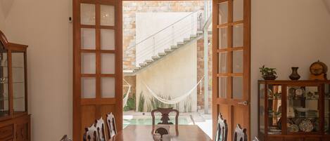 A dining area with a wooden table and chairs, a chandelier, and a view of a staircase leading to a balcony.