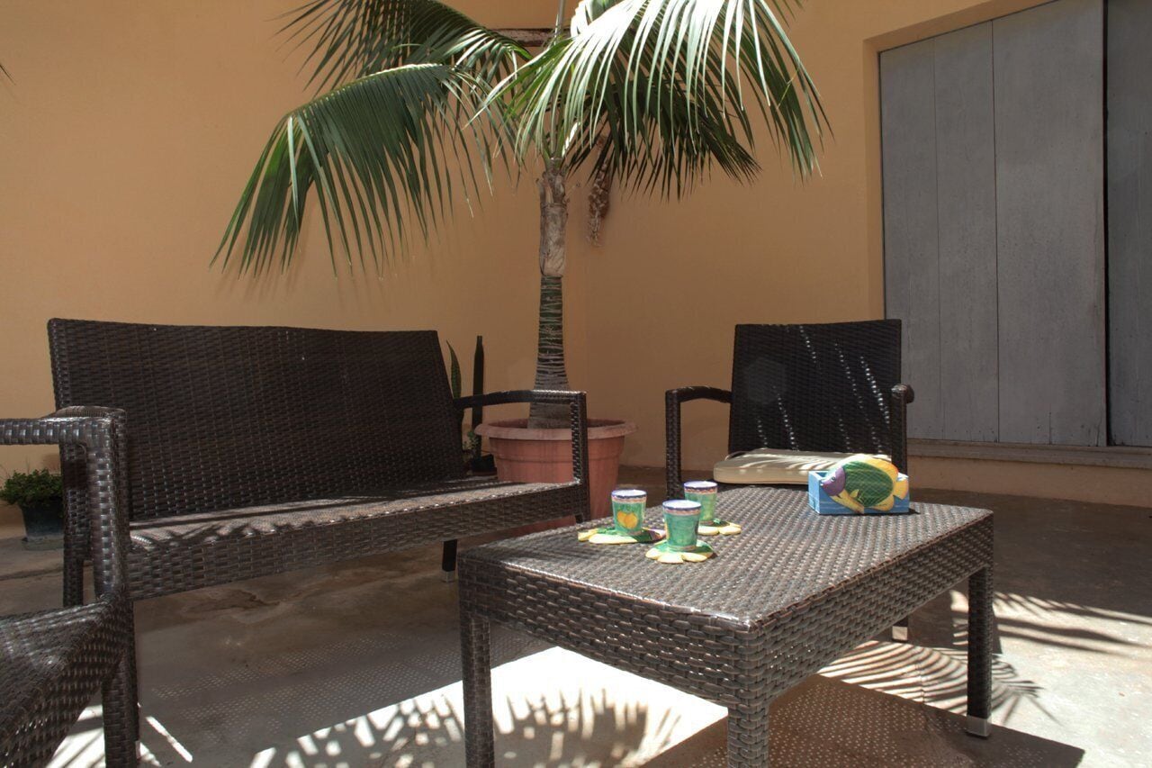 An outdoor seating area with wicker furniture, a palm tree, and a table with decorative items.