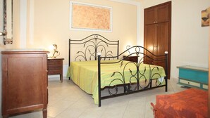 Quarto com cama, mesa de cabeceira, guarda-roupa de madeira e cômoda.