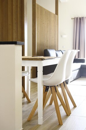 A dining area with a white table and chairs, a wooden partition, and a sofa in the background. - Quinta do Mocho Turismo Rural (Faro)