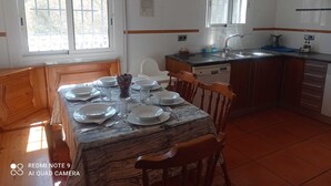 A modern kitchen with a dining area, featuring a marble table, wooden chairs, and a built-in dishwasher.