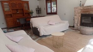 A living room with a sofa set, a small round coffee table, and a stone fireplace.