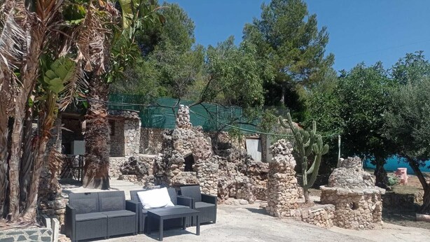 An outdoor seating area with wicker furniture and stone structures.