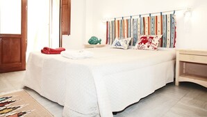 A neatly arranged bedroom with a bed, bedside tables, and a window with curtains. - I tre Golfi Azzurra (San Vito Lo Capo)