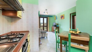 Una cocina con estufa a gas, microondas y comedor con mesa y sillas.