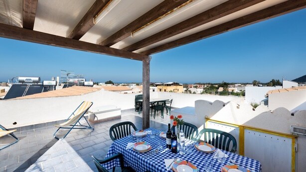 Terraza en la azotea con una mesa para dos, con vistas a un paisaje urbano.