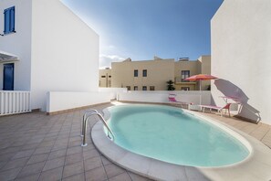 En säsongsöppen utomhuspool, parasoller och solstolar