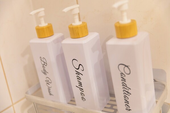 Three bottles of shampoo, conditioner, and body wash on a white shelf. - Villa Mirela (Cibaca)