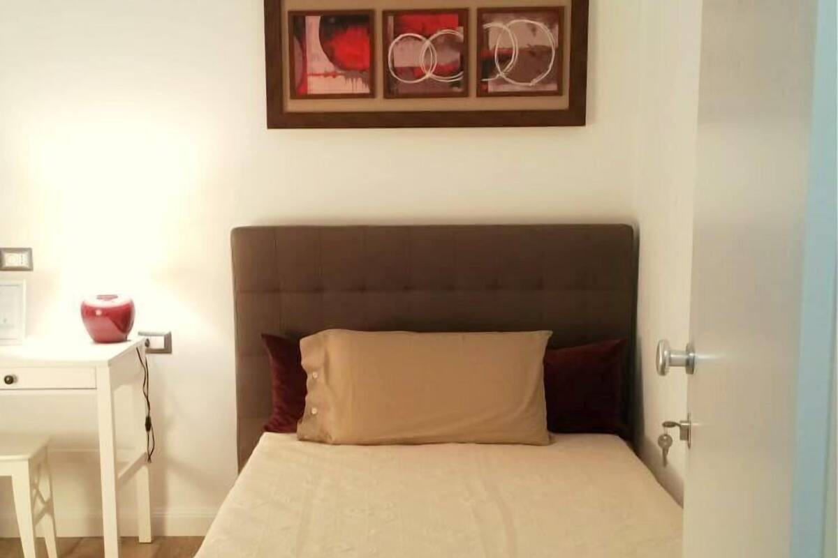 Un dormitorio con cama, mesita de noche y un cuadro colgado en la pared.