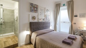 Un dormitorio con cama, ducha y ventana con cortinas.