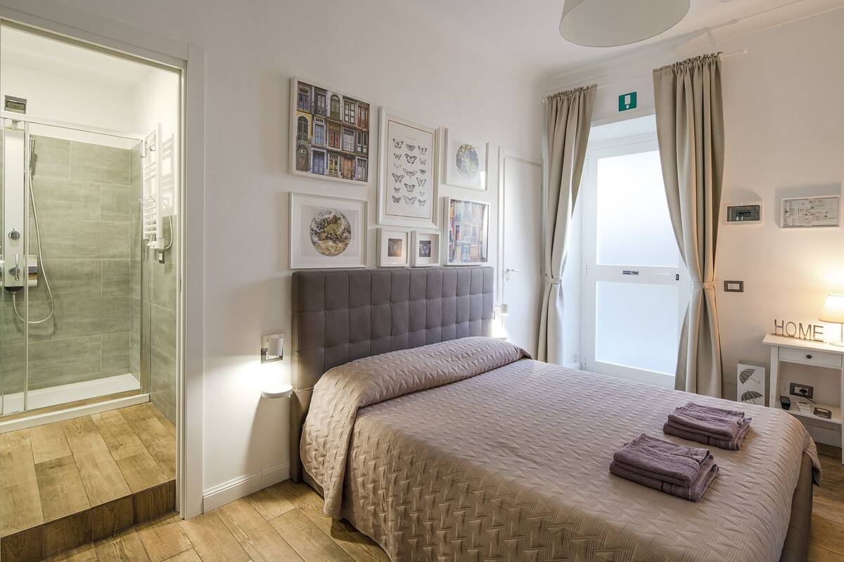 Un dormitorio con cama, ducha y ventana con cortinas.