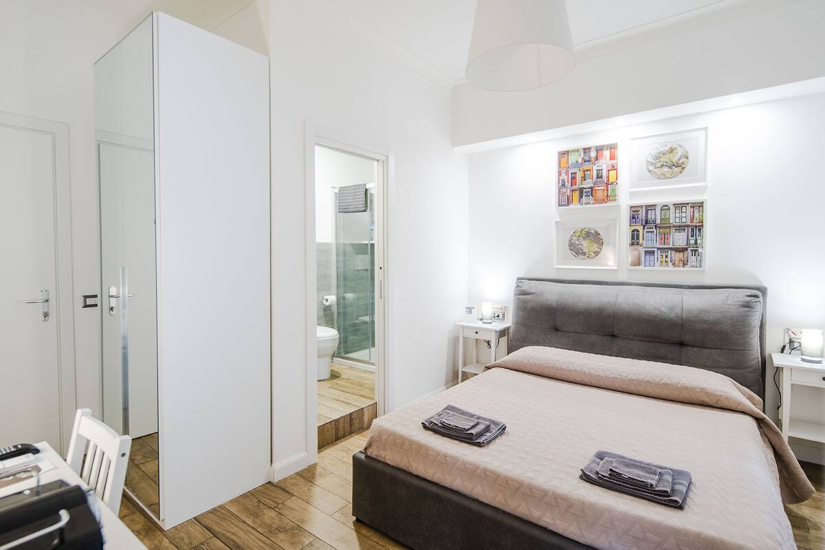 Un dormitorio moderno con una cama grande, una mesita de noche y un armario.
