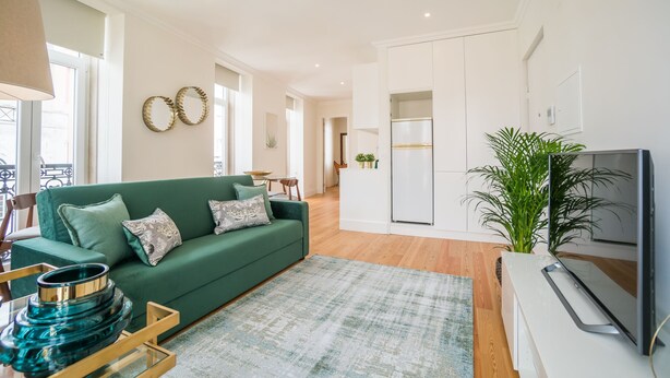A modern living room with a green sofa, a glass coffee table, and a flat-screen TV.