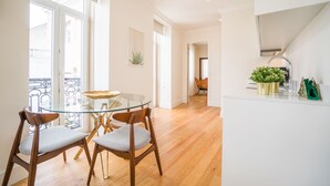A modern kitchen with a white countertop, a glass table, and wooden chairs.