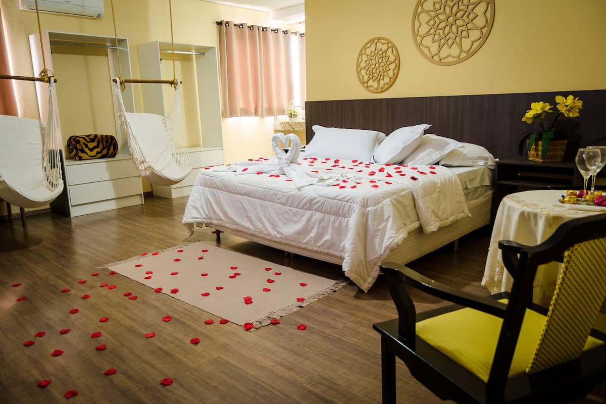 Une chambre d’hôtel avec un lit, une chaise, une table ornée d’un vase de fleurs et un élément décoratif mural.