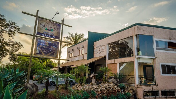 Un hôtel appelé « Vale do Caffe », avec une enseigne, une voiture garée devant et un mur de pierre orné de plantes.