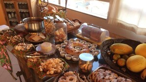 Une table de buffet proposant une variété d’aliments, notamment du pain, des pâtisseries et des fruits.