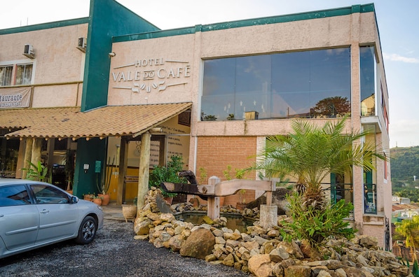 A hotel named "Hotel Valdo Cafe" with a large window, a stone facade, and a car parked in front.