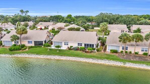 A residential area with houses, some with attached garages, and a body of water in the foreground. - Lake View Villa with a 1 Car Garage, 2 Bedrooms in Lakeside of Naples, Fl (Naples)