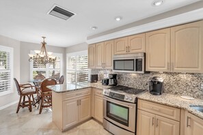 A kitchen with a central island, stainless steel appliances, and a view to the outside. - Lake View Villa with a 1 Car Garage, 2 Bedrooms in Lakeside of Naples, Fl (Naples)