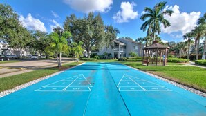 A blue shuffleboard court with a gazebo and palm trees in the background. - Lake View Villa with a 1 Car Garage, 2 Bedrooms in Lakeside of Naples, Fl (Naples)