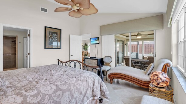 A bedroom with a large bed, a desk, a chair, and a view of the outside. - Lake View Villa with a 1 Car Garage, 2 Bedrooms in Lakeside of Naples, Fl (Naples)