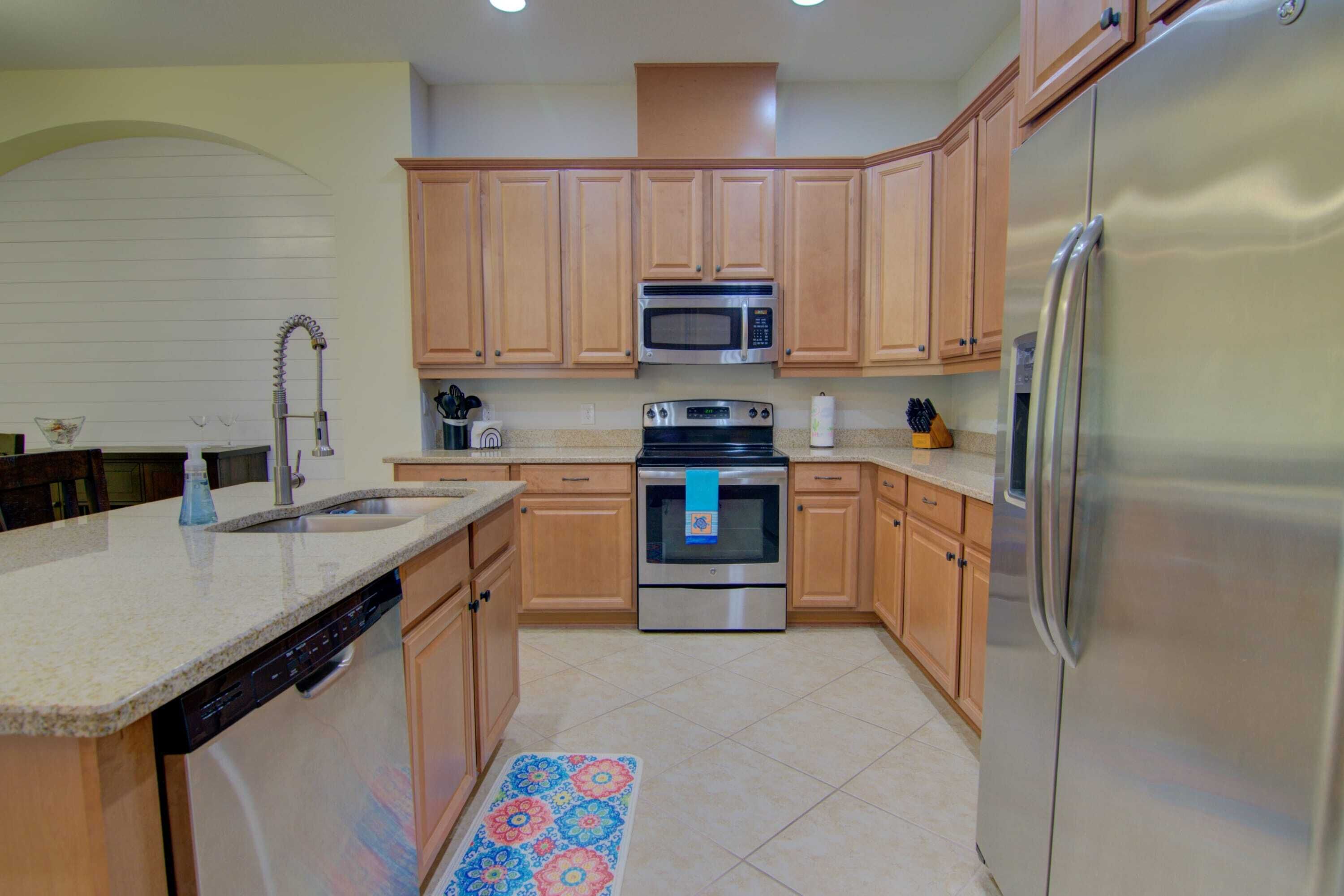 A kitchen with wooden cabinets, a stainless steel refrigerator, a microwave, an oven, and a dishwasher.