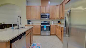 A kitchen with wooden cabinets, a stainless steel refrigerator, a microwave, an oven, and a dishwasher.