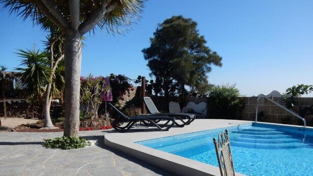 Una piscina con sillas de descanso y un patio de piedra.