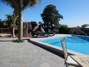 Una piscina con sillas de descanso y un patio de piedra.
