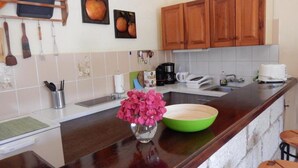 Una cocina con armarios de madera, una encimera, un fregadero, una cafetera y un florero con flores.