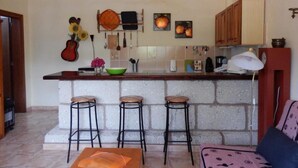 Una cocina con una isla central, taburetes de bar y una guitarra en la pared.