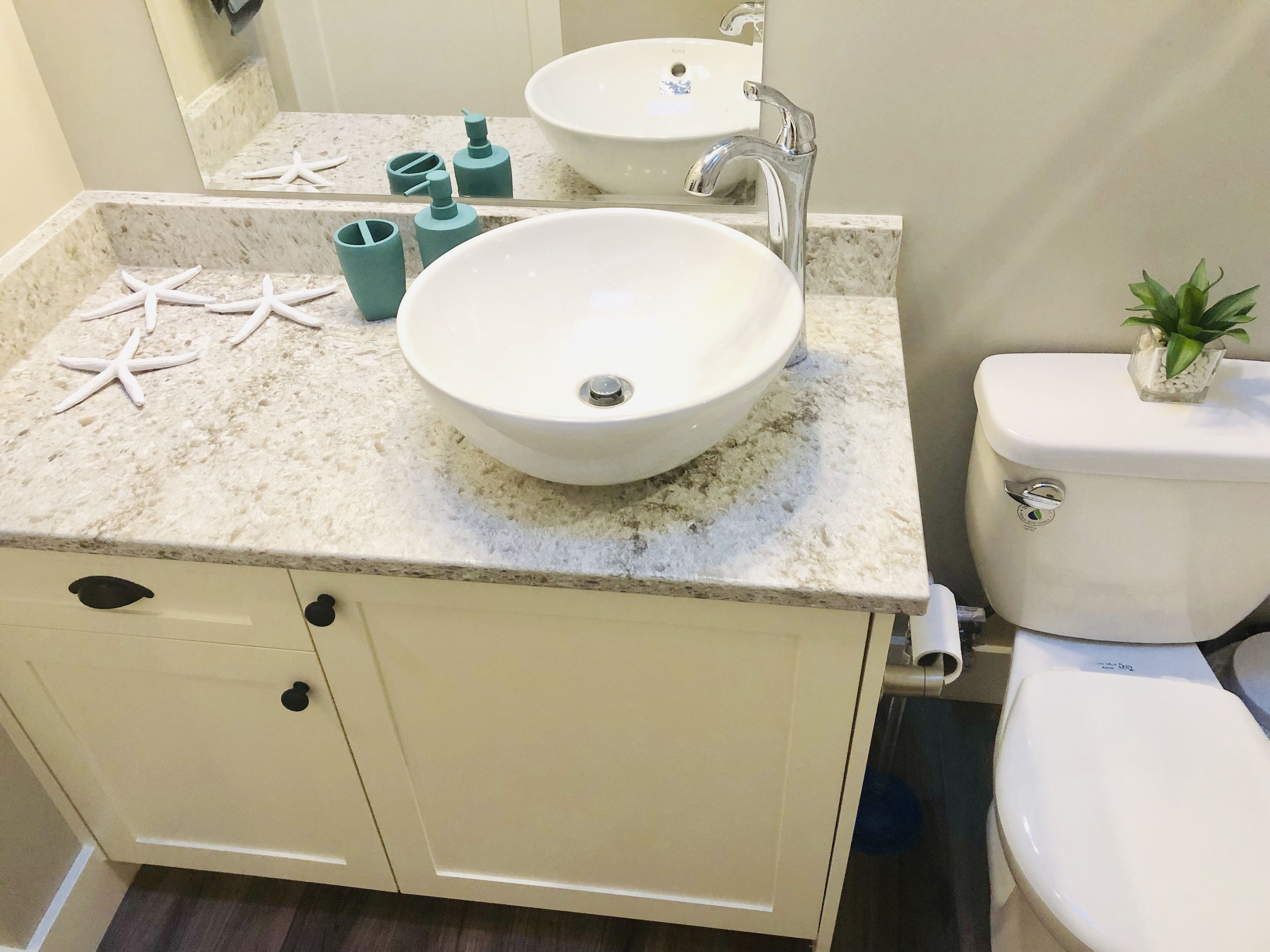 Une salle de bain avec un lavabo blanc, des toilettes et un meuble avec des tiroirs.