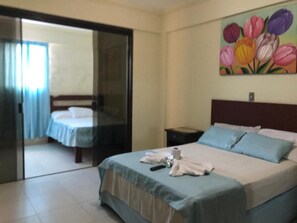 A hotel room with a bed, a nightstand, and a painting of tulips on the wall. - Hotel Viru Viru II (Santa Cruz)
