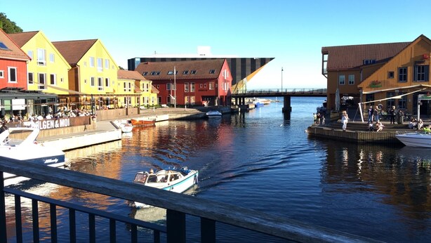 A canal with boats, colorful buildings, and a bridge in the background.