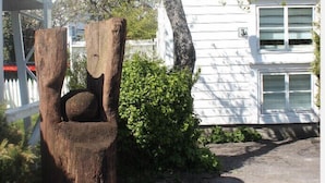 A tree sculpture in a garden area with a white building in the background.