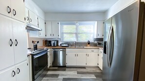 A modern kitchen with white cabinets, stainless steel appliances, and a patterned floor.
