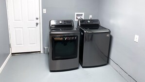 A laundry room with two stacked washers and dryers, a white door, and a gray wall.