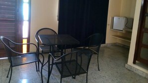 A small, enclosed patio area with a table and four chairs, a dark curtain, a refrigerator, and a door with a window. - Mayan Hotel Boutique (Mérida)
