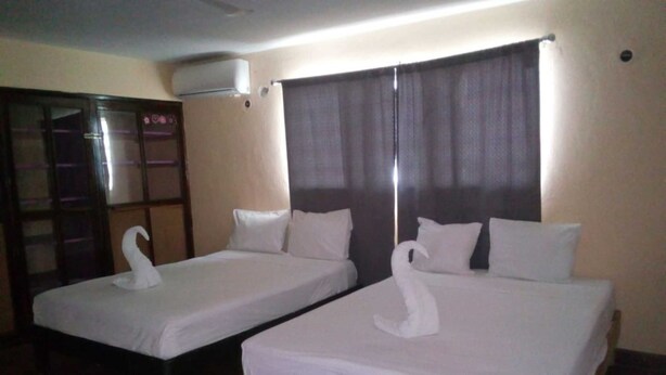 Two single beds with white linens and swan-shaped pillows, wooden headboards, and a dark curtain. - Mayan Hotel Boutique (Mérida)