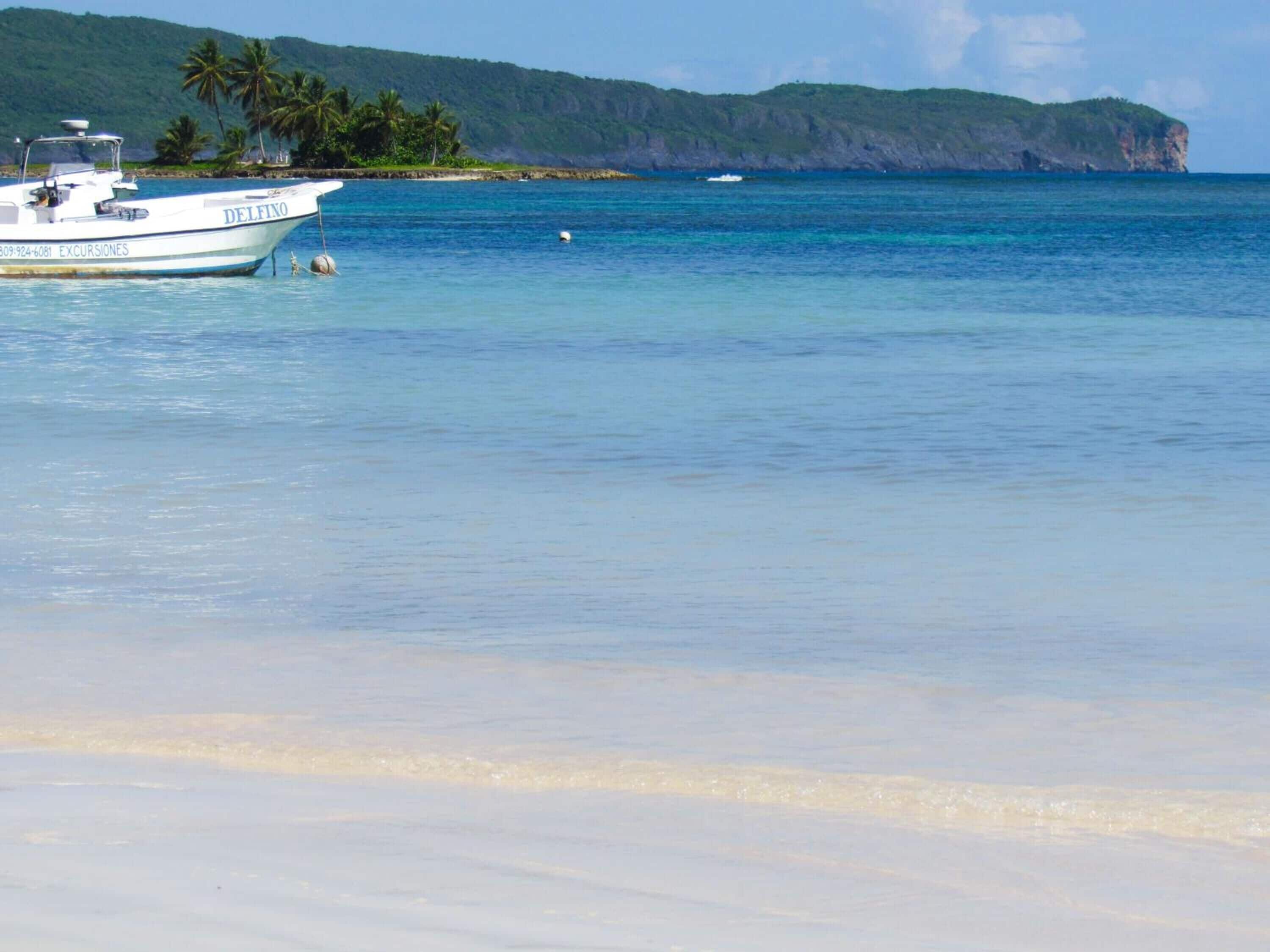 A boat named Delfino with a clear view of the surrounding water and distant land.