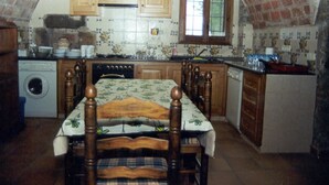 Una cucina compatta con mobili in legno, schienale piastrellato, una finestra e un'area pranzo con tavolo e sedie.