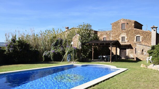 Una piscina con un edificio in pietra sullo sfondo.